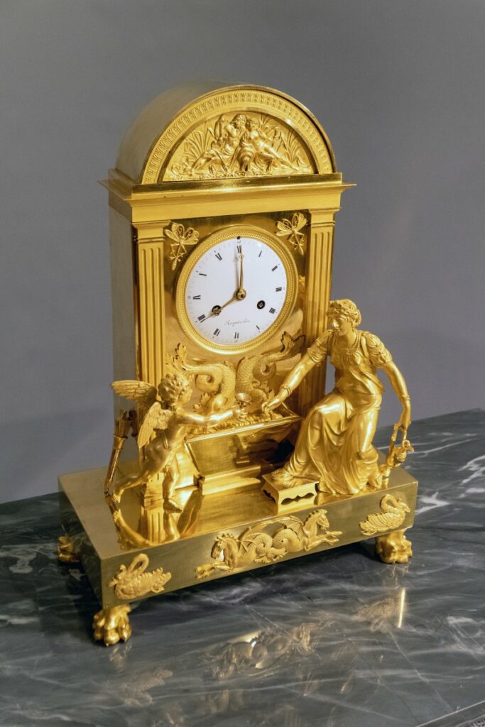 Pendule borne en bronze doré : 'L'amour se désaltérant'.